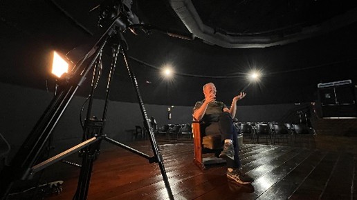 Imagem artística de uma pessoa sentada em um palco.